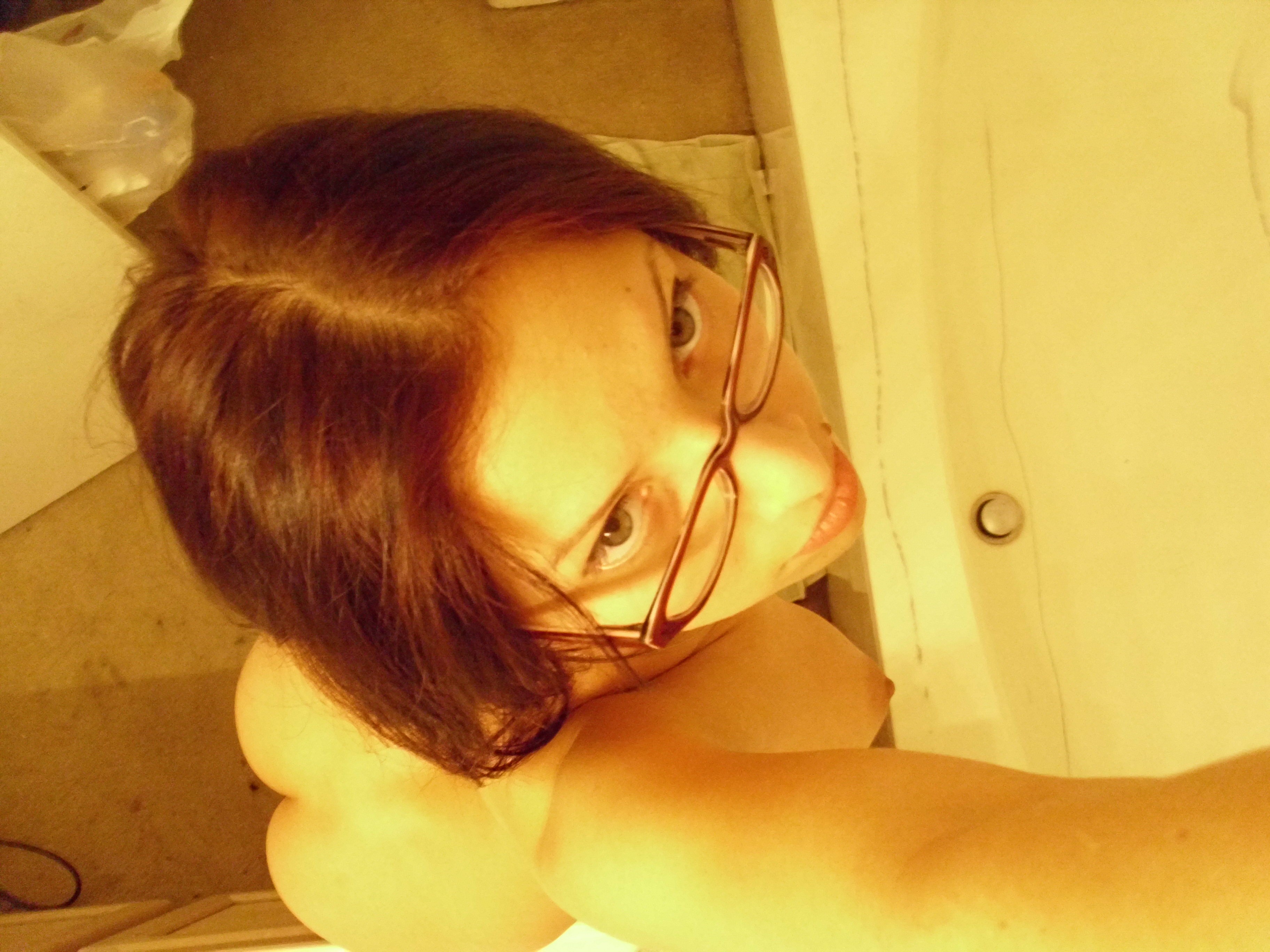 Брюнетка в очках любуется собой в ванной перед зеркалом